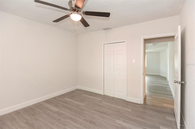 unfurnished bedroom featuring visible vents, a closet, light wood-style flooring, and baseboards