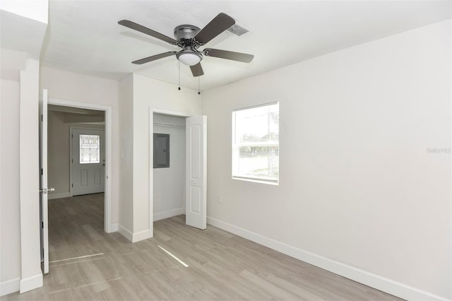 unfurnished bedroom featuring light wood-type flooring, electric panel, baseboards, and a closet