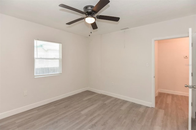 unfurnished room featuring baseboards, a ceiling fan, visible vents, and light wood-style floors