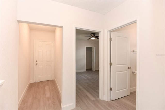 hallway featuring light wood finished floors and baseboards