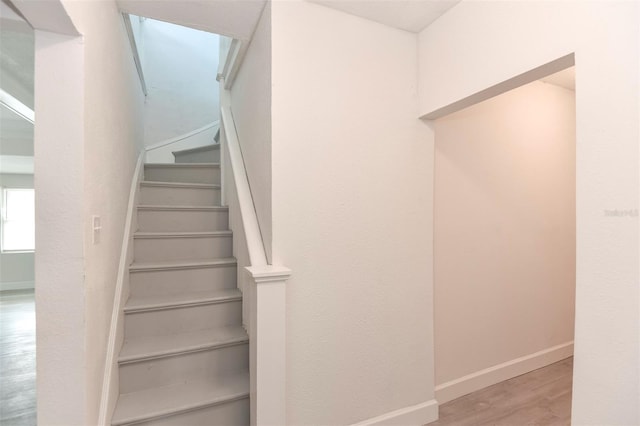 staircase featuring wood finished floors and baseboards