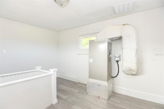 hallway with baseboards, visible vents, wood finished floors, and an upstairs landing