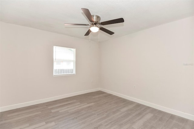 empty room featuring baseboards, ceiling fan, and light wood-style floors