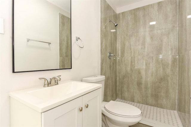 bathroom featuring tiled shower, vanity, and toilet