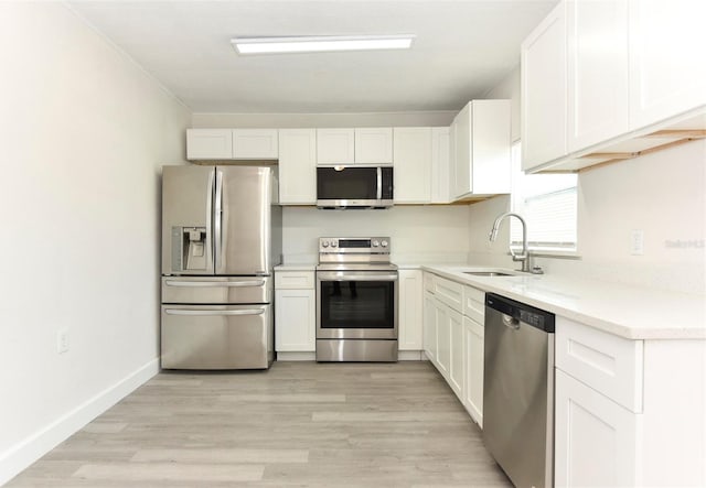 kitchen featuring white cabinets, light wood-type flooring, stainless steel appliances, and a sink