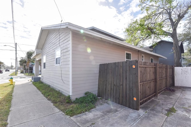 view of side of home with central air condition unit and fence