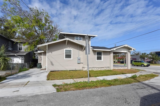 view of home's exterior with concrete driveway, an attached carport, and fence