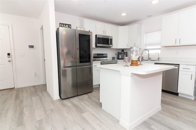 kitchen featuring white cabinets, sink, light wood-type flooring, appliances with stainless steel finishes, and a kitchen island