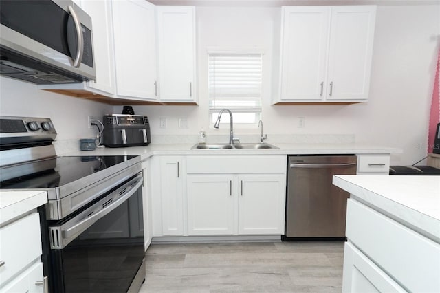 kitchen featuring sink, white cabinets, stainless steel appliances, and light wood-type flooring