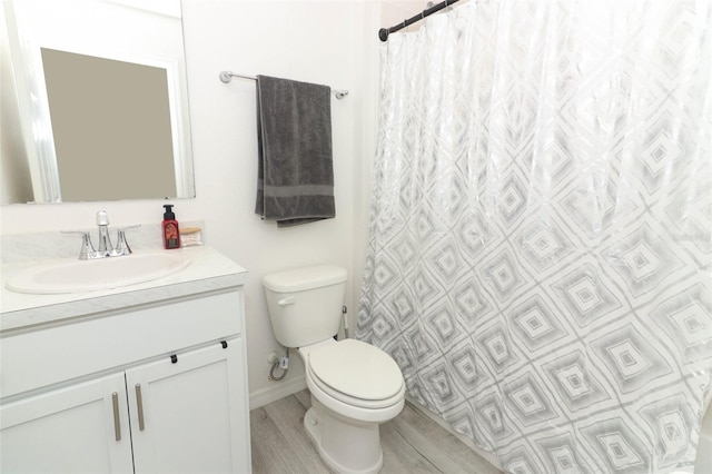 bathroom featuring wood-type flooring, vanity, toilet, and walk in shower