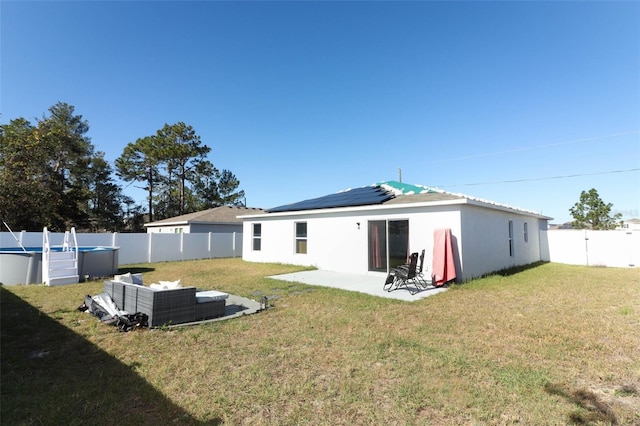 back of house with outdoor lounge area, solar panels, a patio, and a lawn