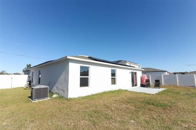 back of house with a lawn, solar panels, cooling unit, and a patio area