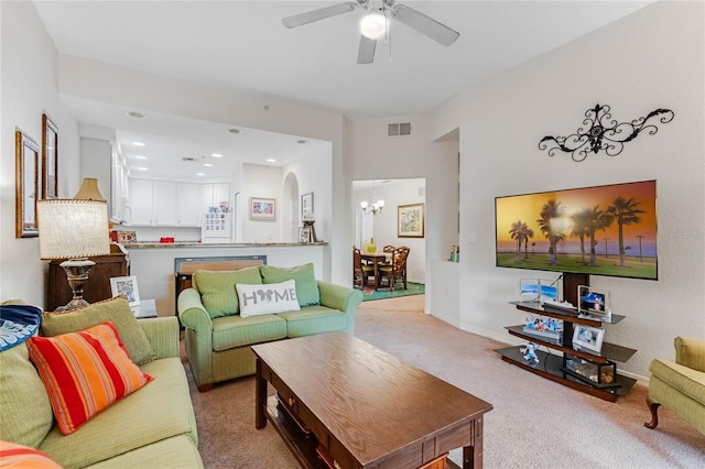 carpeted living room featuring ceiling fan with notable chandelier