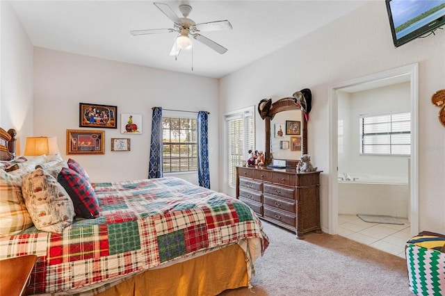 bedroom featuring light colored carpet, ensuite bath, multiple windows, and ceiling fan