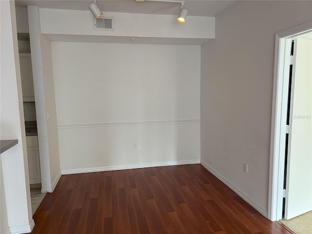 unfurnished room featuring dark hardwood / wood-style floors and track lighting