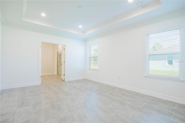 unfurnished room featuring a raised ceiling, a healthy amount of sunlight, and crown molding