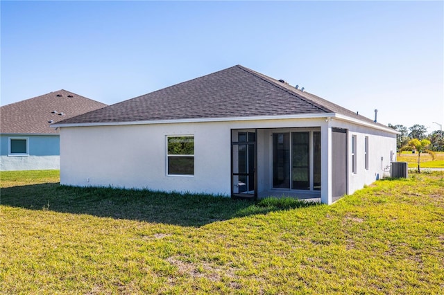 rear view of property with a sunroom, a yard, and central AC