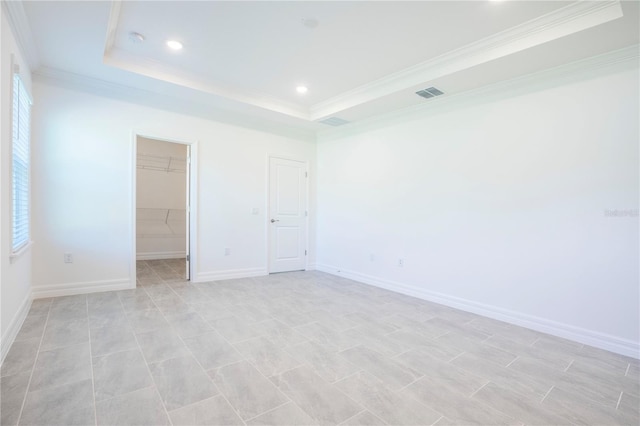 empty room featuring a raised ceiling and crown molding