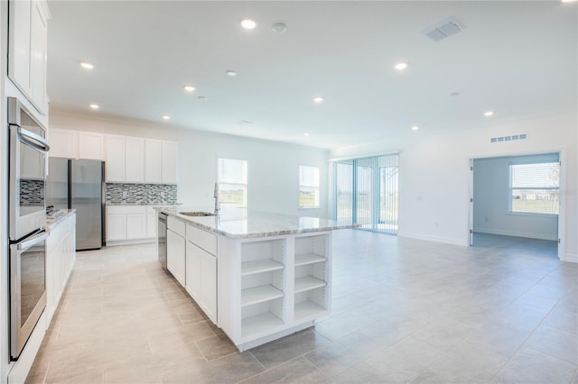 kitchen featuring white cabinets, stainless steel appliances, a kitchen island with sink, and sink