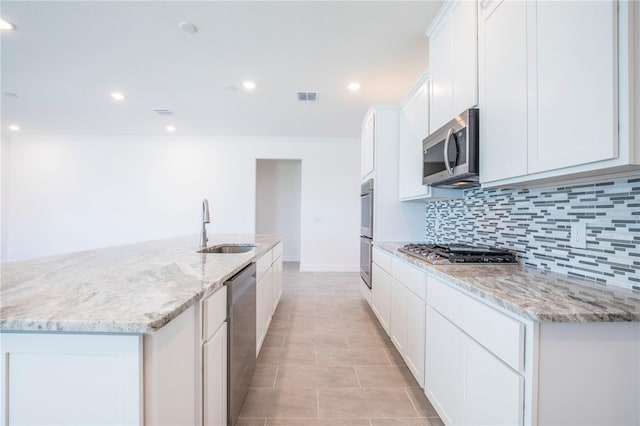 kitchen with sink, light stone counters, a kitchen island with sink, white cabinets, and appliances with stainless steel finishes