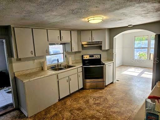 kitchen featuring electric stove, sink, a healthy amount of sunlight, and a textured ceiling