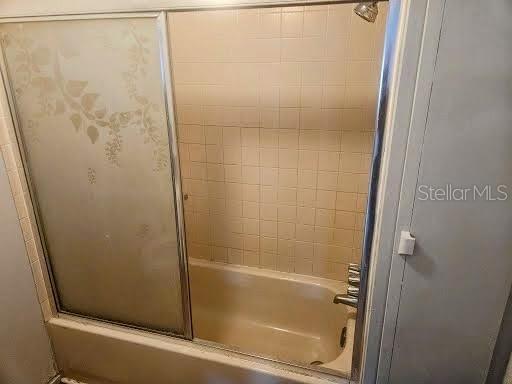 bathroom with bath / shower combo with glass door