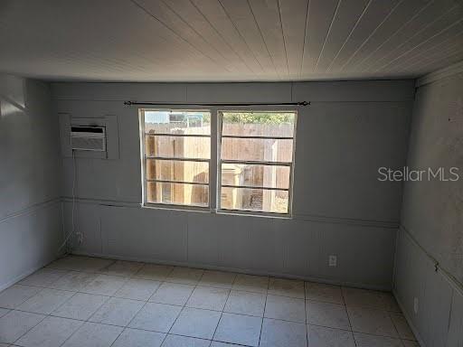 empty room featuring a wall unit AC and wooden ceiling