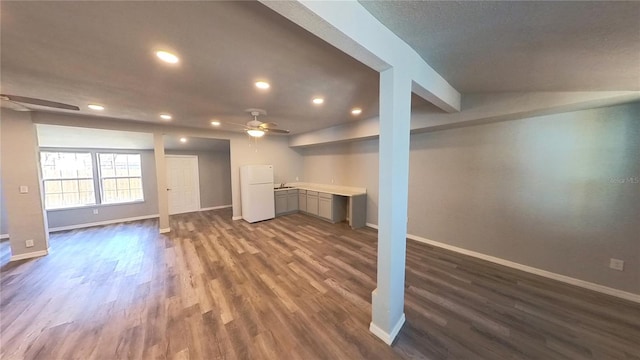 below grade area featuring freestanding refrigerator, dark wood finished floors, baseboards, and ceiling fan