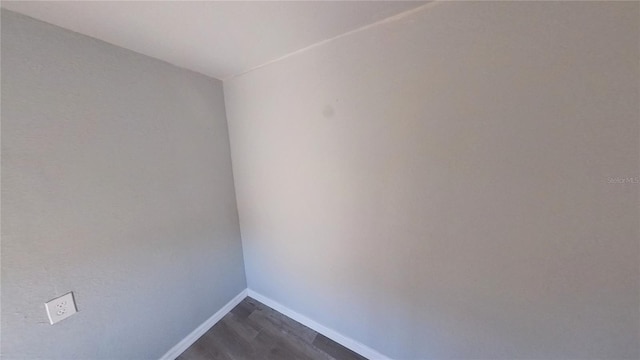 unfurnished room featuring dark wood-type flooring and baseboards