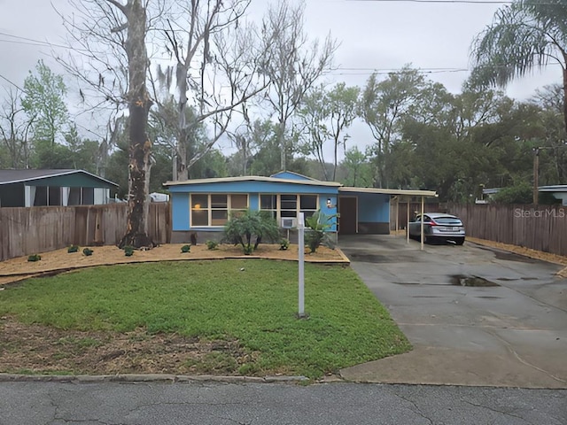 view of front of house with driveway, an attached carport, a front lawn, and fence