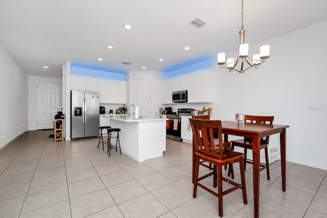 kitchen featuring sink, stainless steel appliances, an inviting chandelier, an island with sink, and pendant lighting