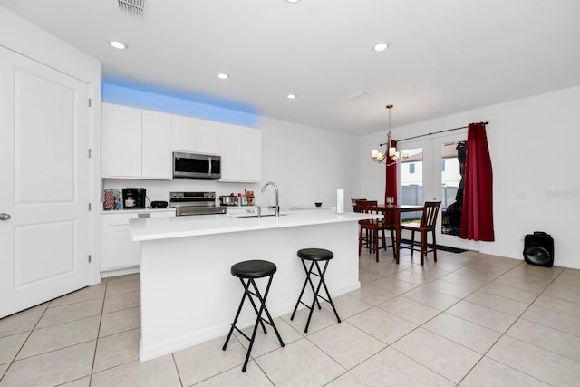 kitchen with decorative light fixtures, stainless steel appliances, a center island with sink, and sink