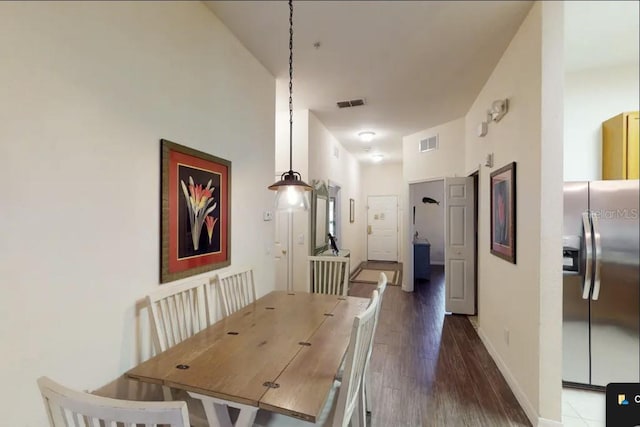 dining room with dark hardwood / wood-style floors and a towering ceiling