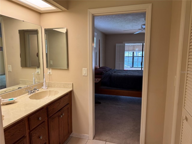 bathroom with tile patterned floors, vanity, ceiling fan, and a textured ceiling