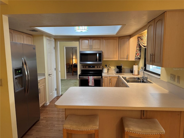 kitchen featuring kitchen peninsula, a breakfast bar, stainless steel appliances, and sink