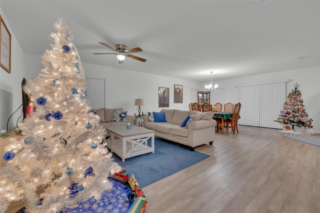 living room with hardwood / wood-style floors and ceiling fan with notable chandelier