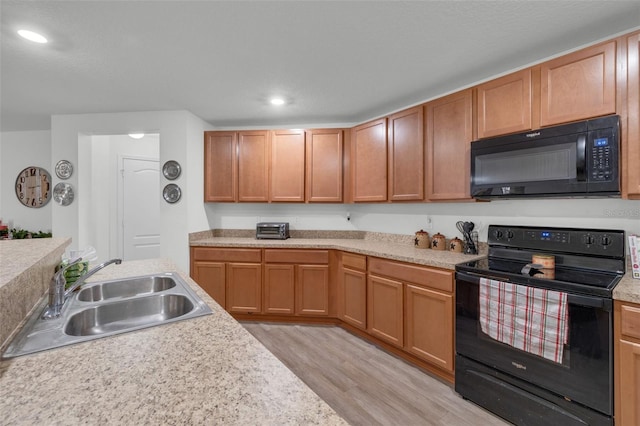 kitchen with sink, black appliances, and light hardwood / wood-style floors