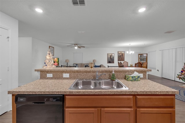 kitchen featuring hardwood / wood-style floors, dishwasher, ceiling fan with notable chandelier, sink, and an island with sink