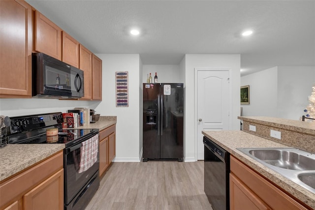 kitchen with a textured ceiling, sink, light hardwood / wood-style floors, and black appliances