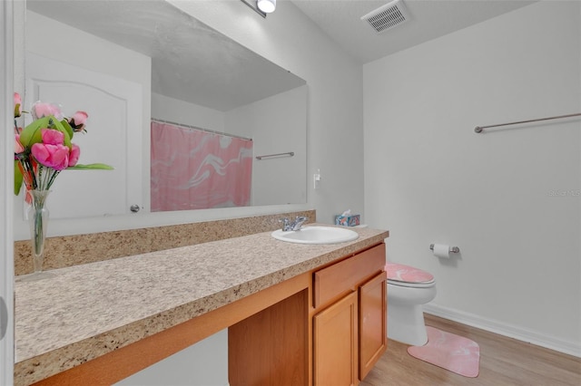 bathroom featuring vanity, hardwood / wood-style flooring, and toilet