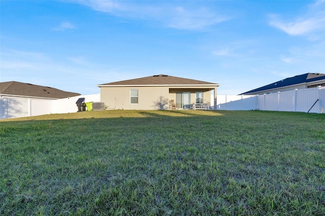 rear view of property with central AC and a lawn