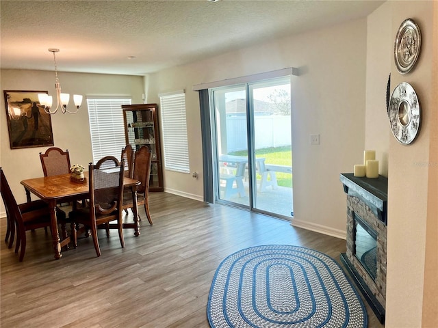2325 Crossandra St, Mascotte, FL 34753 - dining room with wood finished floors, a chandelier, a stone fireplace, and a textured ceiling