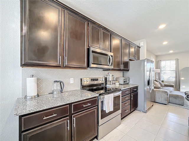 kitchen with dark brown cabinets, backsplash, stainless steel appliances, and light tile patterned floors