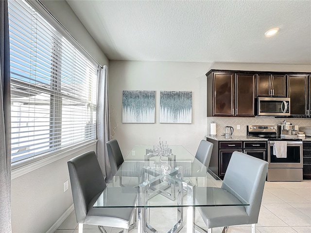 dining area featuring light tile patterned floors, a healthy amount of sunlight, and a textured ceiling