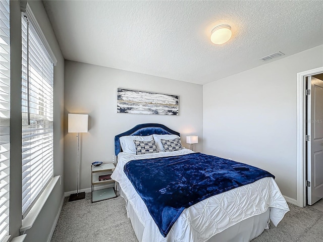 bedroom featuring a textured ceiling and light colored carpet