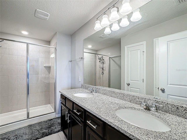 bathroom featuring tile patterned floors, vanity, a shower with shower door, and a textured ceiling