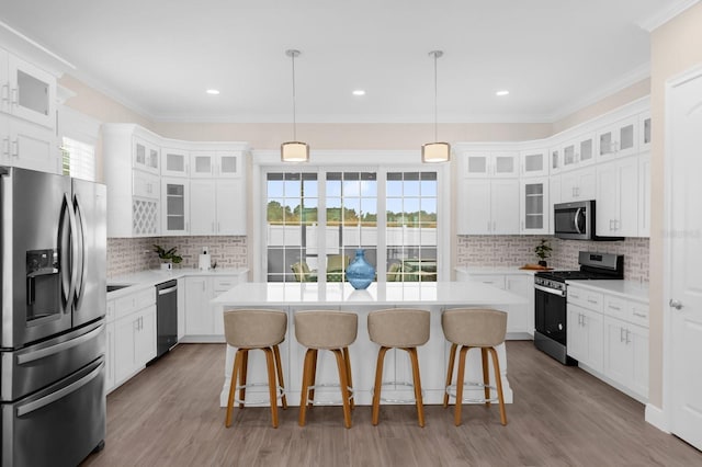 kitchen featuring white cabinets, stainless steel appliances, a kitchen island, and a healthy amount of sunlight