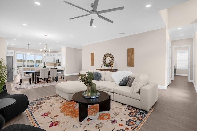 living room with hardwood / wood-style floors, ceiling fan with notable chandelier, and ornamental molding