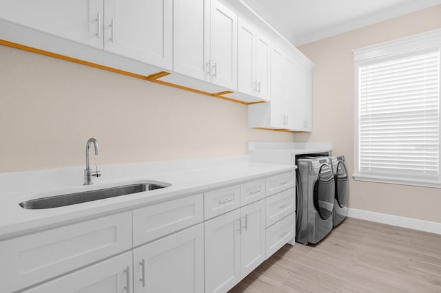 washroom featuring light hardwood / wood-style flooring, cabinets, sink, and washing machine and clothes dryer