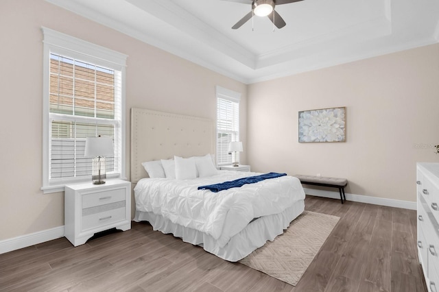 bedroom featuring a raised ceiling, ceiling fan, light hardwood / wood-style floors, and ornamental molding